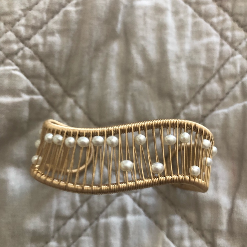 A gold wire cuff bracelet with pearl beads